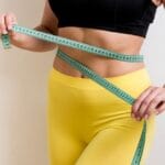 Woman with measurement tape and flat stomach.